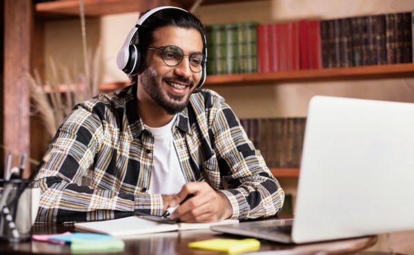 Positive Indian Student Guy At Laptop Learning Online At Home